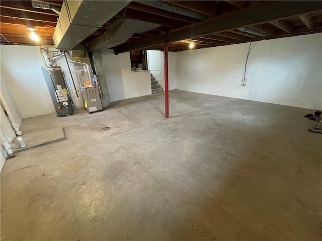 unfinished basement featuring heating unit, stairway, and gas water heater