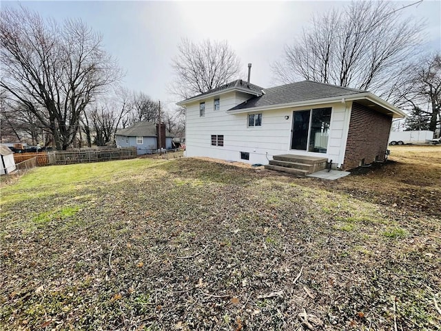 rear view of property with crawl space, a yard, roof with shingles, and fence