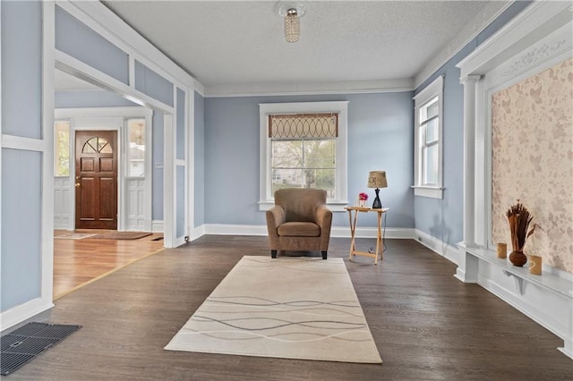 sitting room with baseboards, visible vents, ornamental molding, wood finished floors, and a textured ceiling