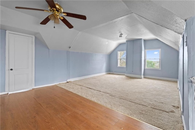 additional living space with lofted ceiling, a ceiling fan, a textured ceiling, wood finished floors, and baseboards