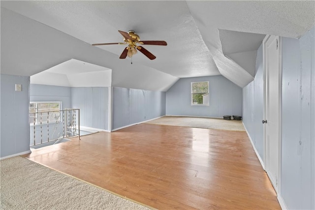 additional living space with lofted ceiling, ceiling fan, a textured ceiling, and wood finished floors