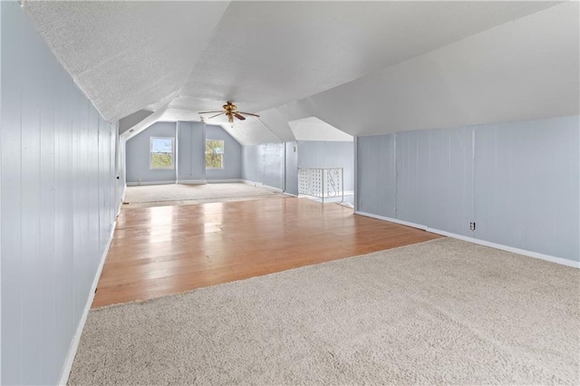 additional living space with lofted ceiling, a ceiling fan, carpet flooring, a textured ceiling, and wood finished floors