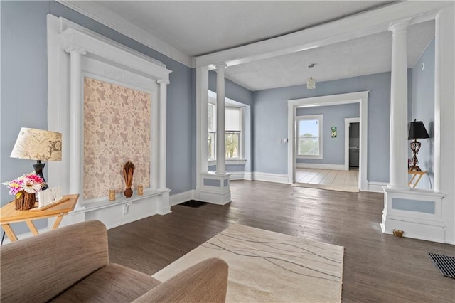 sitting room with baseboards, wood finished floors, visible vents, and ornate columns