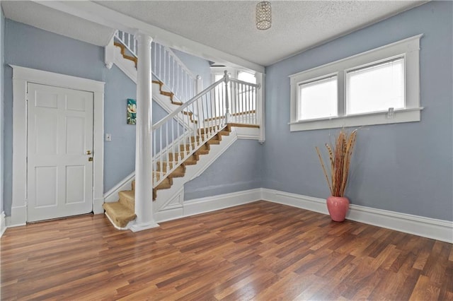 foyer with stairs, baseboards, and wood finished floors