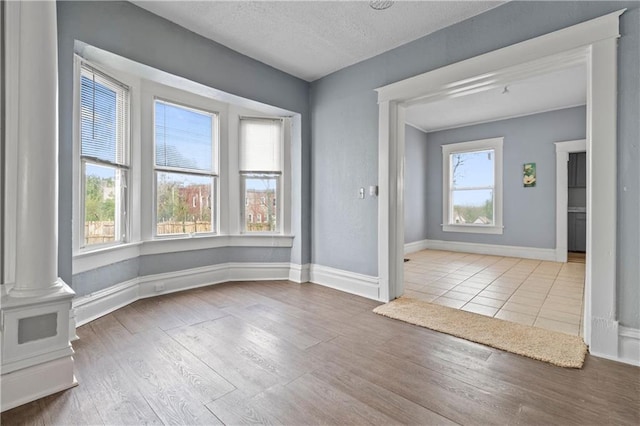 interior space with a wealth of natural light, a textured ceiling, baseboards, and wood finished floors