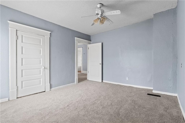 unfurnished bedroom featuring a textured ceiling, carpet floors, visible vents, and baseboards