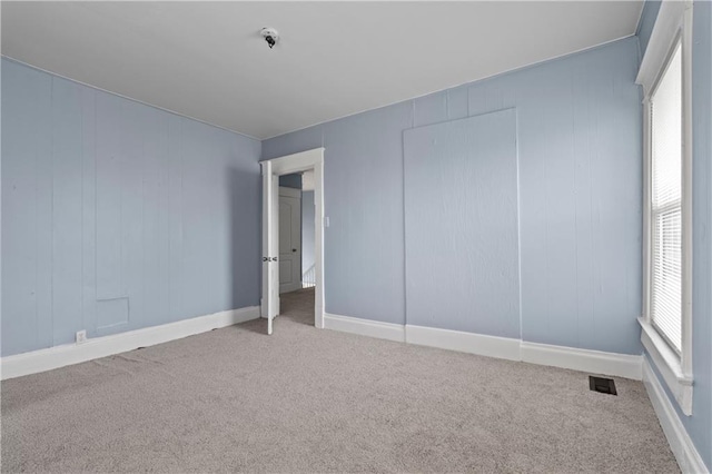 carpeted empty room with visible vents and baseboards