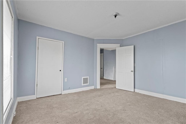 unfurnished bedroom with carpet, multiple windows, visible vents, and ornamental molding