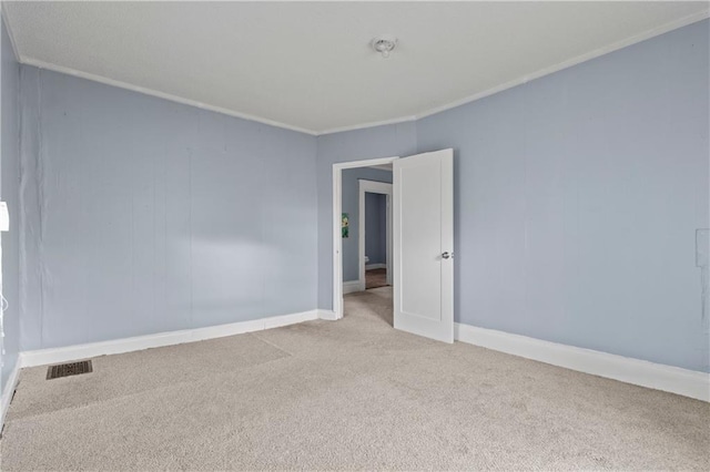 empty room with baseboards, carpet, visible vents, and crown molding