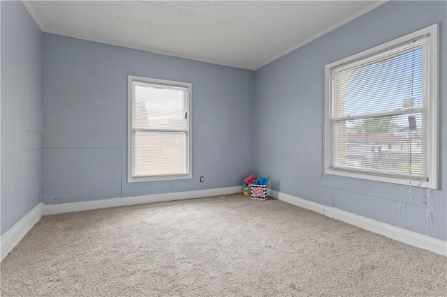 carpeted empty room with a healthy amount of sunlight, a textured ceiling, and baseboards