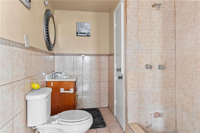 bathroom featuring tiled shower, toilet, tile patterned floors, vanity, and tile walls