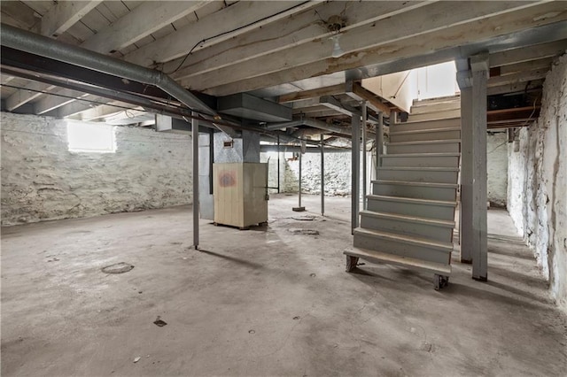 unfinished basement with heating unit and stairs