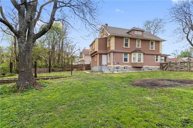 rear view of property featuring a yard and fence