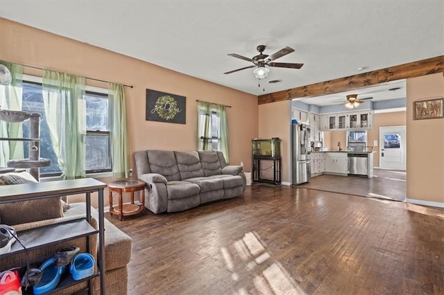 living area featuring dark wood finished floors, baseboards, and ceiling fan