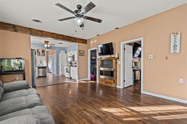 living room featuring visible vents, baseboards, ceiling fan, beam ceiling, and wood finished floors