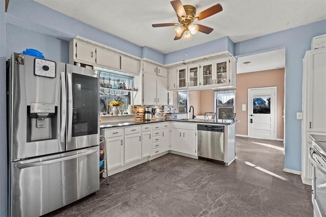 kitchen featuring a peninsula, stainless steel appliances, white cabinetry, a ceiling fan, and a sink