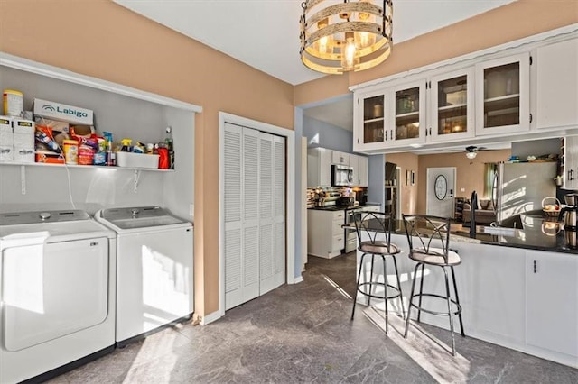 clothes washing area featuring a sink, laundry area, a ceiling fan, and washer and clothes dryer