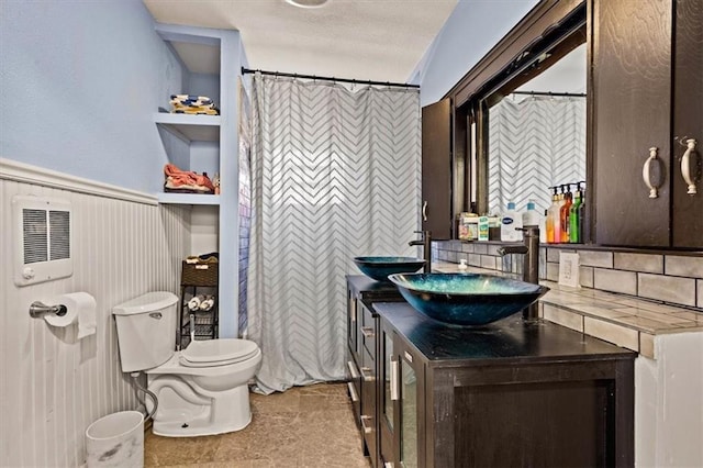 bathroom with backsplash, toilet, wainscoting, and vanity