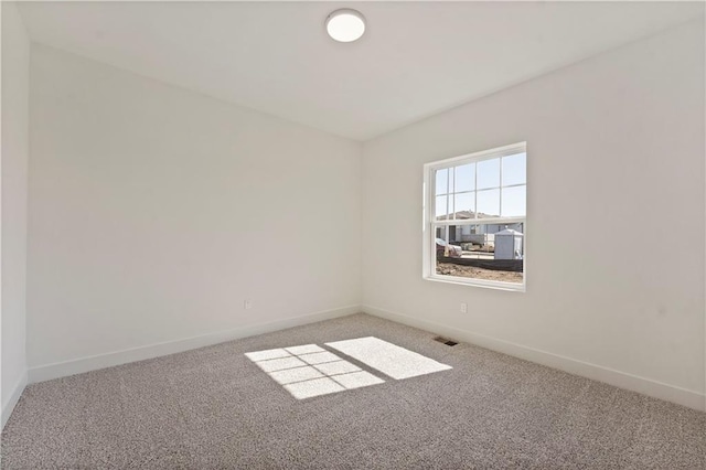 carpeted spare room featuring visible vents and baseboards