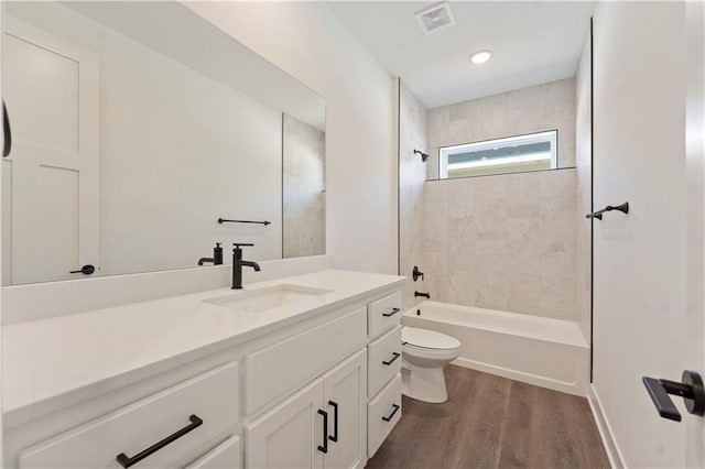 bathroom with shower / bath combination, visible vents, toilet, vanity, and wood finished floors