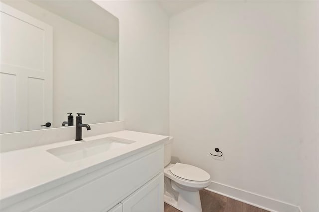 bathroom featuring wood finished floors, vanity, toilet, and baseboards