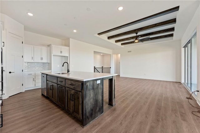 kitchen featuring light wood-style floors, beam ceiling, white cabinetry, and a sink