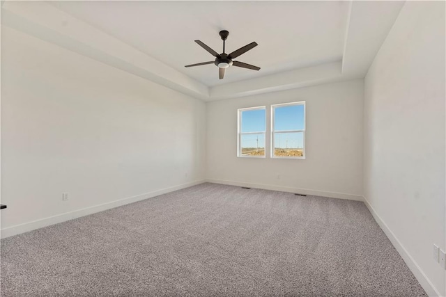 unfurnished room featuring a tray ceiling, a ceiling fan, light colored carpet, and baseboards