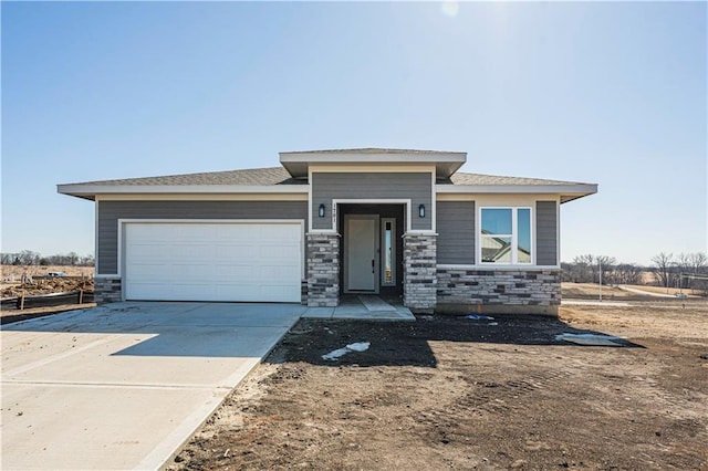 prairie-style home with a garage, stone siding, and concrete driveway