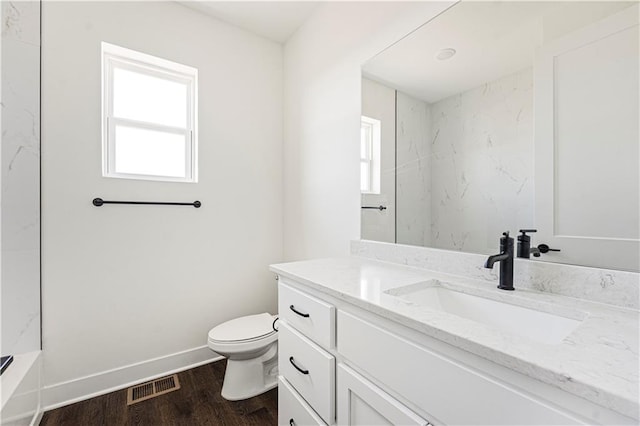 full bathroom with baseboards, visible vents, toilet, wood finished floors, and vanity