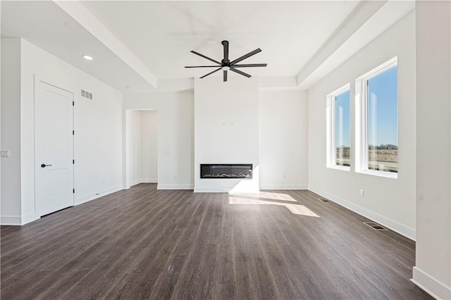 unfurnished living room with dark wood-style flooring, a glass covered fireplace, and visible vents