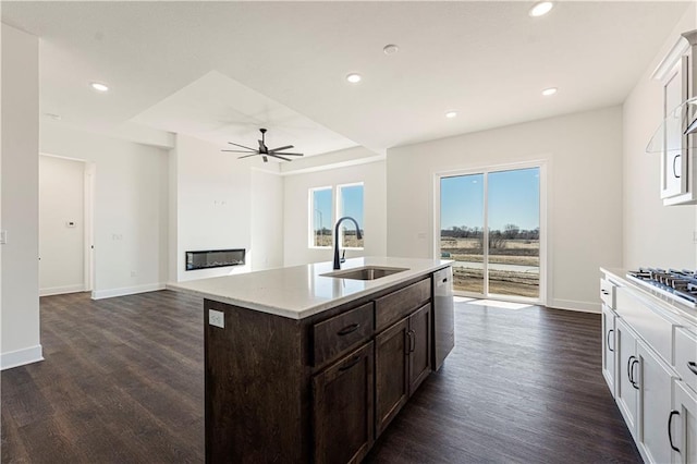 kitchen featuring a glass covered fireplace, dark wood-type flooring, dark brown cabinets, a sink, and recessed lighting