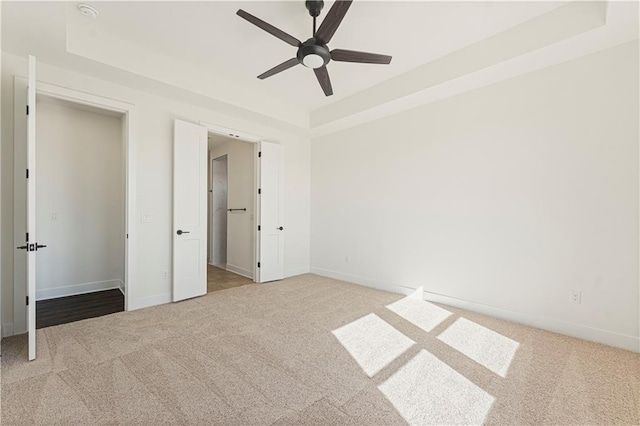 unfurnished bedroom with carpet, a raised ceiling, and baseboards