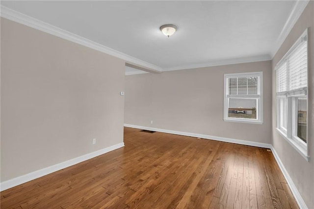 spare room with visible vents, baseboards, hardwood / wood-style floors, and ornamental molding