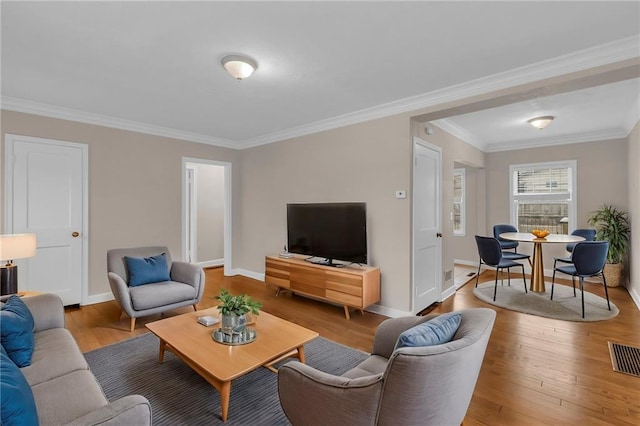 living area featuring hardwood / wood-style flooring, visible vents, and ornamental molding