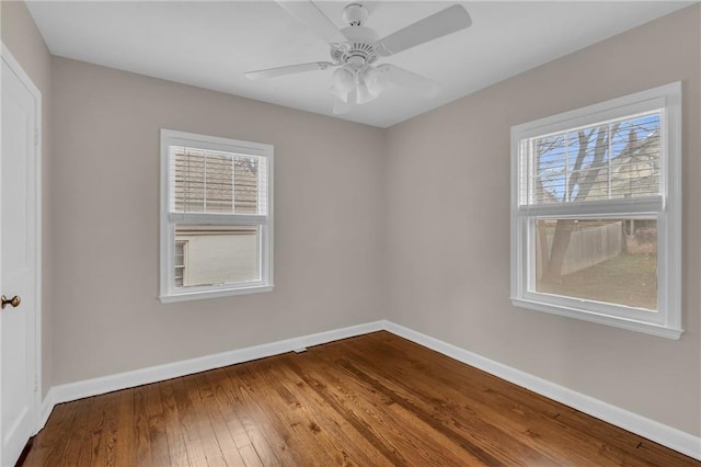 spare room featuring wood-type flooring, a wealth of natural light, and baseboards