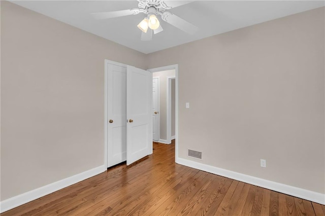 empty room featuring wood finished floors, a ceiling fan, and baseboards