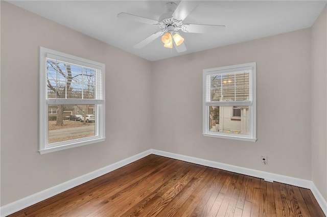 spare room with hardwood / wood-style floors, a ceiling fan, and baseboards