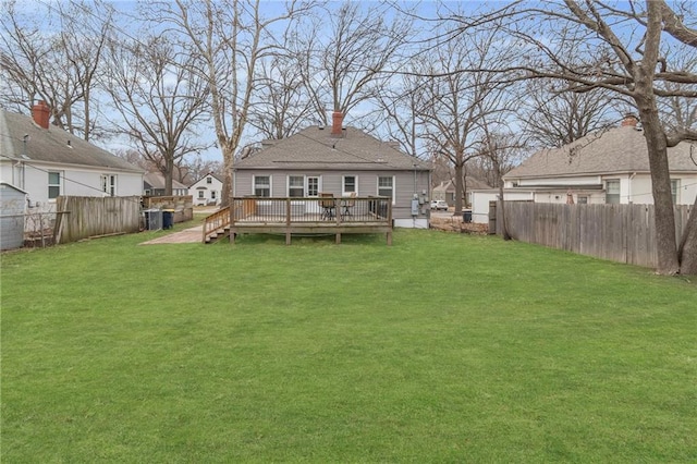 back of house featuring a lawn, a chimney, a fenced backyard, and a wooden deck