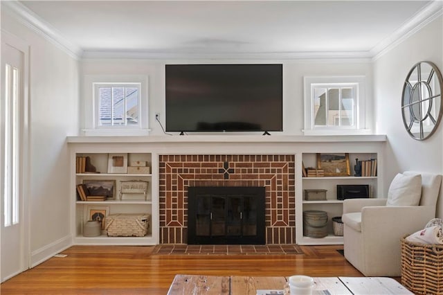 living area featuring crown molding, a brick fireplace, and wood finished floors