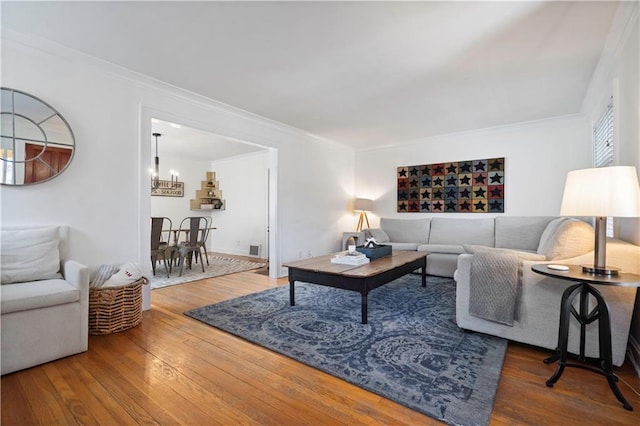 living room featuring visible vents, crown molding, an inviting chandelier, and wood-type flooring