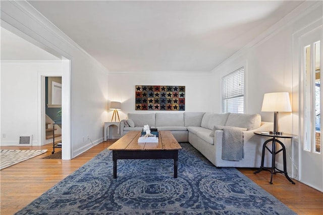 living room with crown molding, wood finished floors, and visible vents