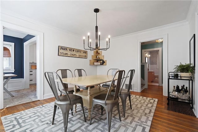 dining area featuring wood finished floors, a chandelier, and ornamental molding