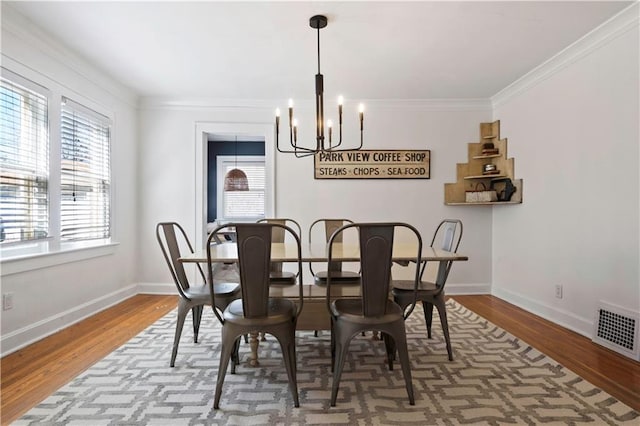 dining area with visible vents, a notable chandelier, wood finished floors, and ornamental molding