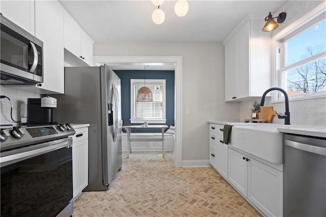 kitchen featuring decorative backsplash, a healthy amount of sunlight, white cabinetry, and appliances with stainless steel finishes