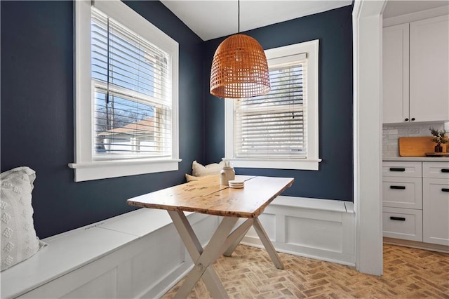 dining space with a wealth of natural light, a wainscoted wall, breakfast area, and brick floor