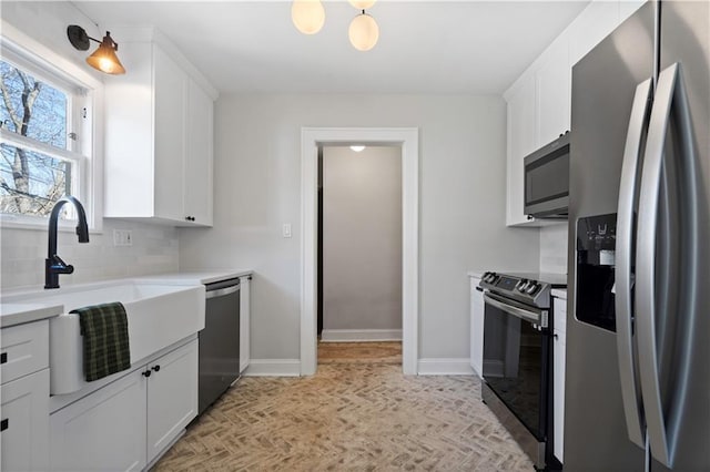 kitchen featuring backsplash, appliances with stainless steel finishes, baseboards, and a sink