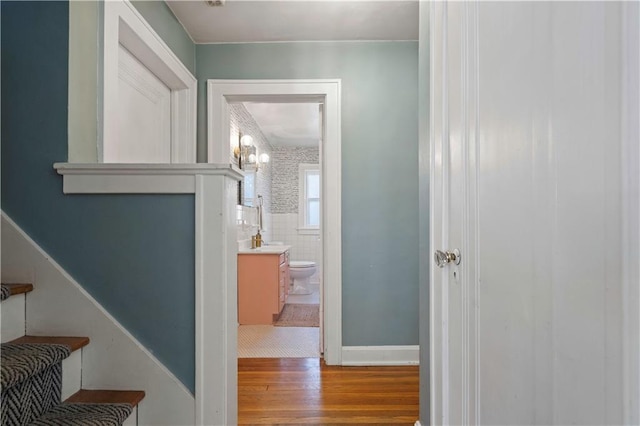 hall with tile walls, stairs, and wood finished floors