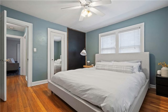 bedroom with a ceiling fan, baseboards, and hardwood / wood-style floors