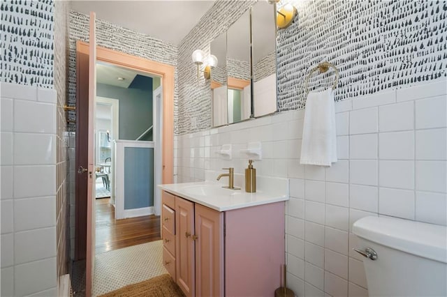 bathroom with toilet, tile walls, and vanity