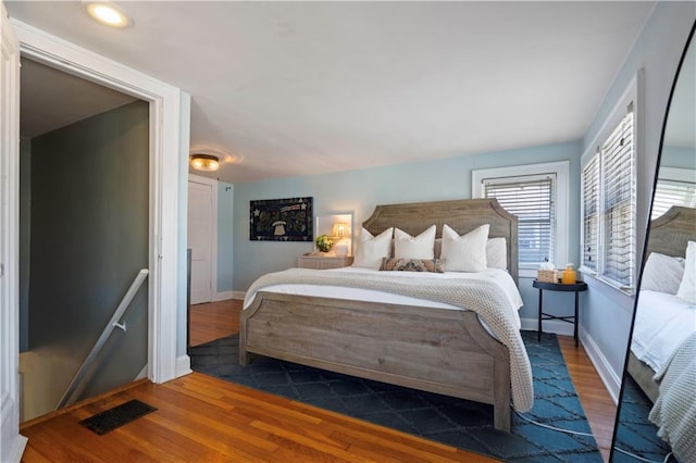 bedroom featuring wood finished floors, visible vents, and baseboards